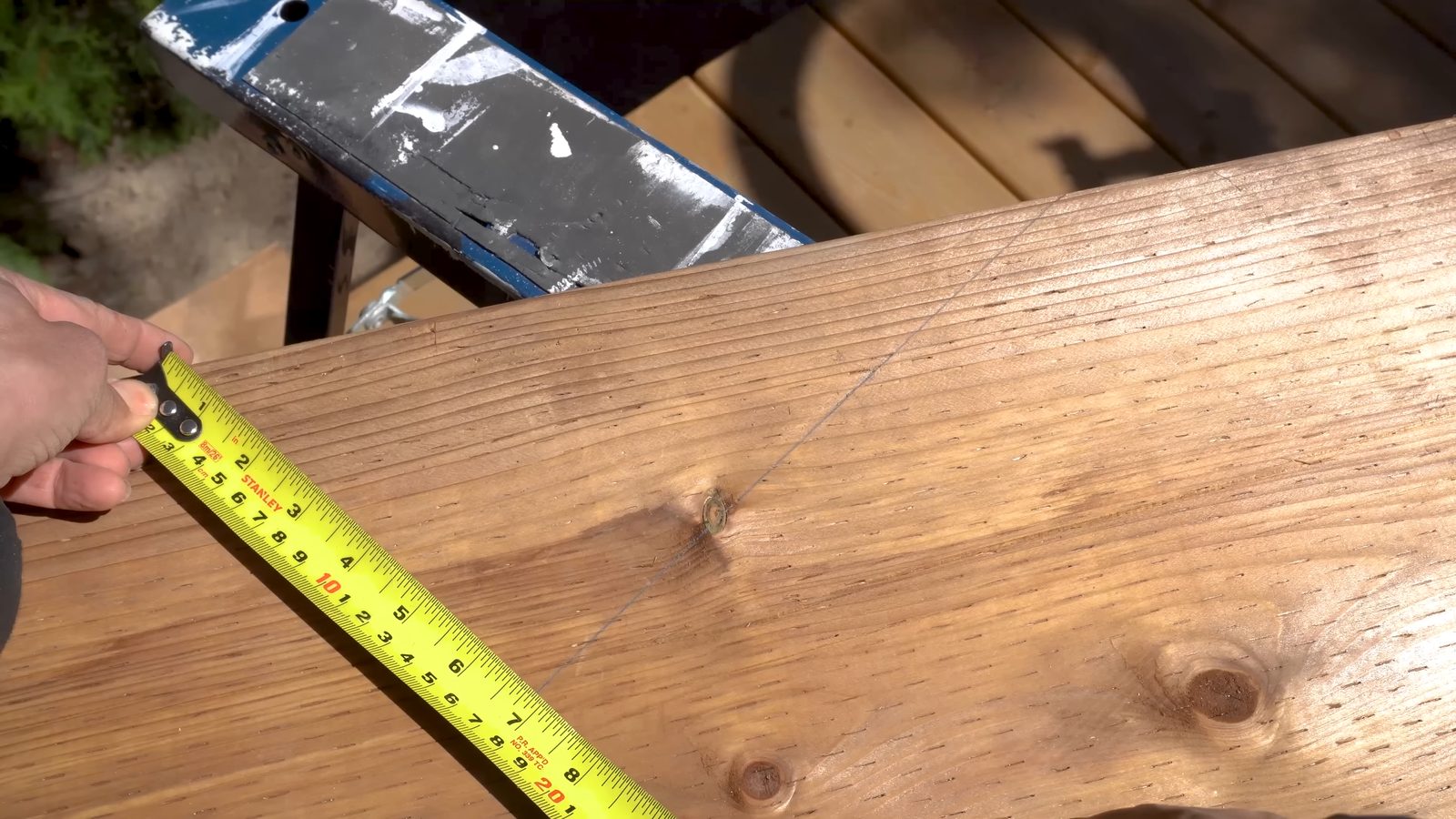 Double-checking a traced deck stair layout line with a tape measure before cutting