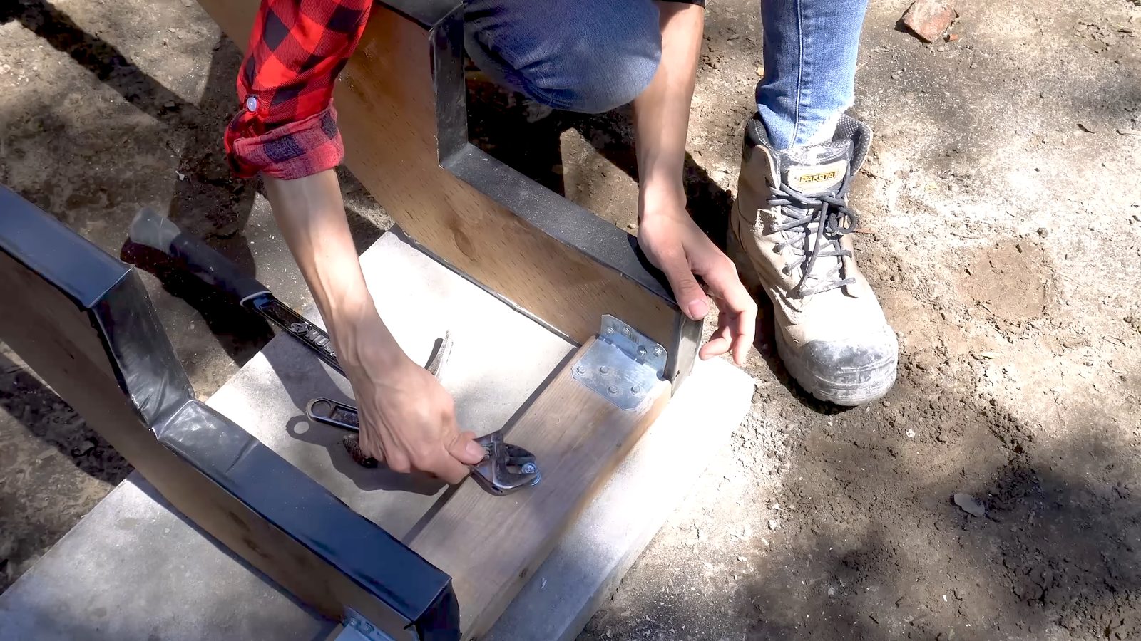 Tightening the wedge anchor with a wrench to secure the base to concrete