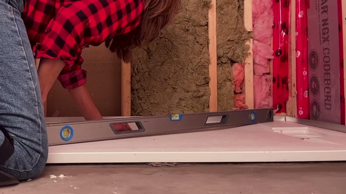 Checking a curbless shower base for level across the diagonals, corner to corner, with a level