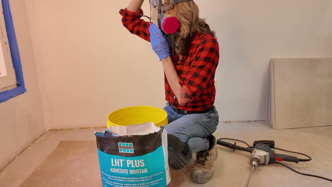 Contractor wearing a respirator mask, goggles and gloves, mixing Laticrete LHT PLUS mortar with a variable-speed mixer