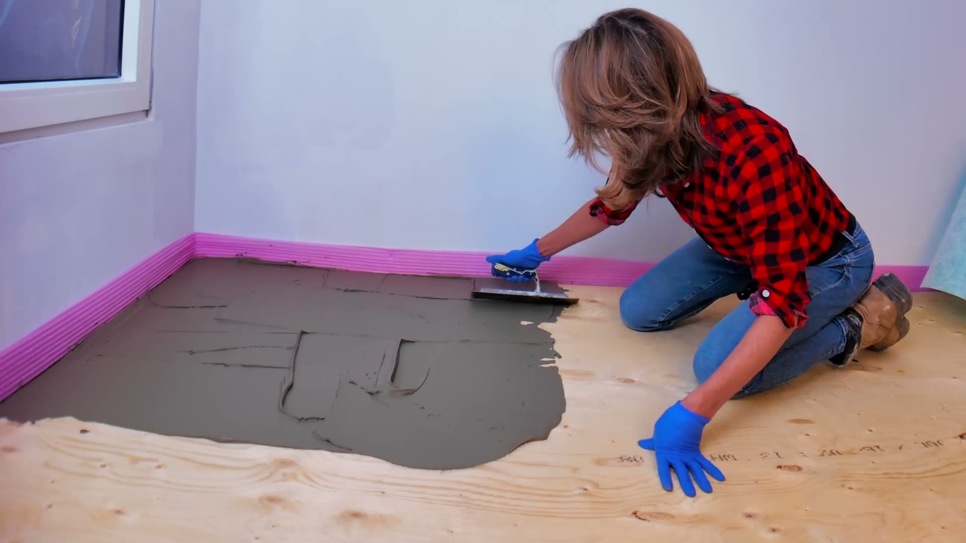 Keying modified mortar into a wood subfloor with the flat side of the trowel before combing