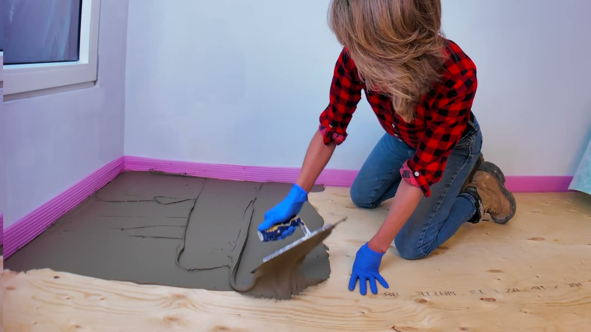 Spreading modified mortar with the flat side of the trowel over a clean plywood subfloor for a tile membrane