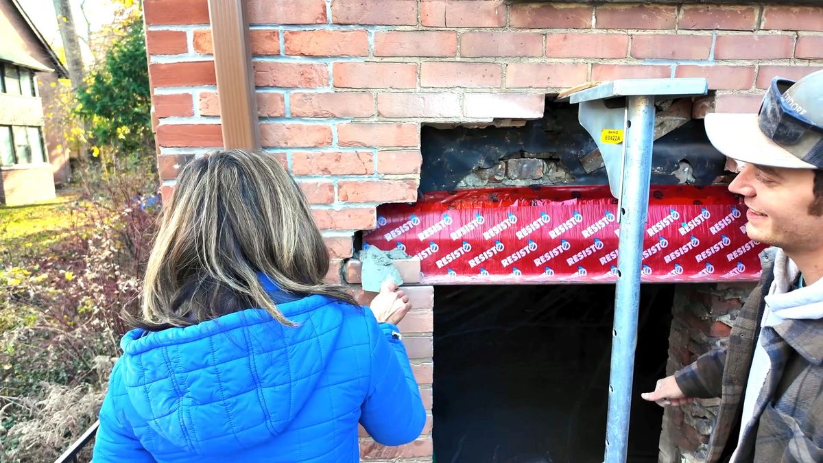 Buttering mortar onto brick as the first course goes back in on the lintel