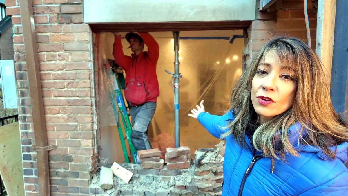Contractor at a widened masonry opening propped with an adjustable steel prop while the brick above is supported
