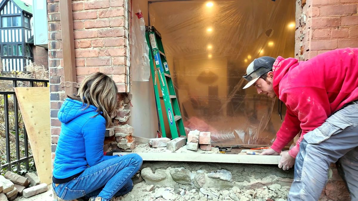 Wet-setting the full-width Indiana Limestone sill into a fresh mortar bed, drip edge out